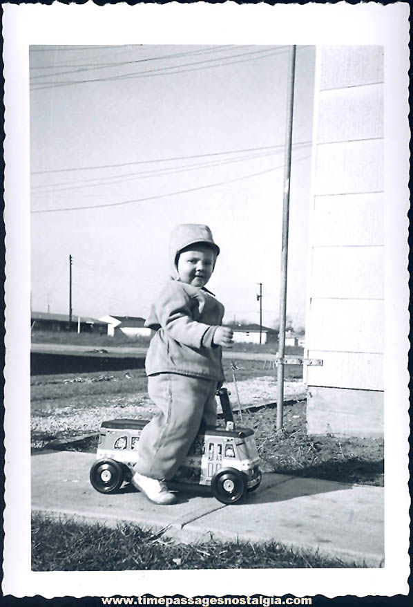 Old Black & White Photograph of Child on an Old Ride On Toy Bus